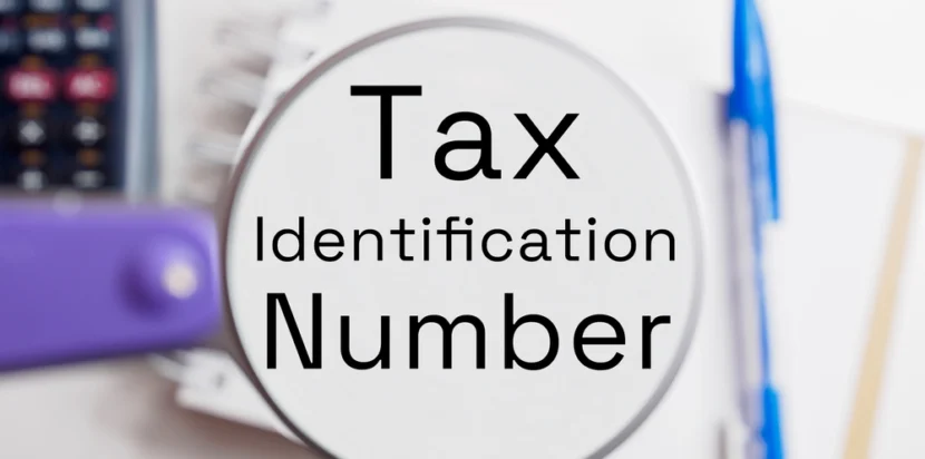 TIN certificate concept shown with magnifying glass highlighting Tax Identification Number and office supplies in the background