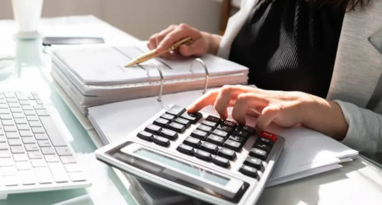 Professional accountant performing asset valuation for visa purpose in Bangladesh using calculator and documents.